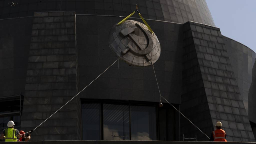 Arbeiter entfernen ein sowjetisches Emblem vom «Mutterlanddenkmal» in Kiew. Die Insignien werden durch ein ukrainisches Emblem ersetzt. Foto: Jae C. Hong/AP/dpa