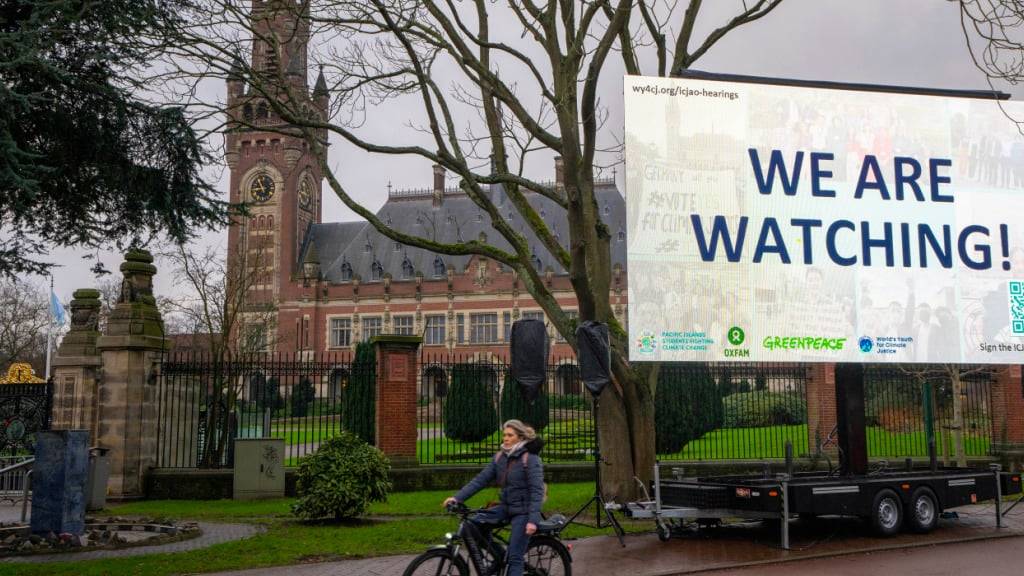 ARCHIV - «We are Watching!» ist auf einem Plakat vor dem Internationalen Gerichtshof in Den Haag zu lesen. Foto: Peter Dejong/AP/dpa/Archivbild