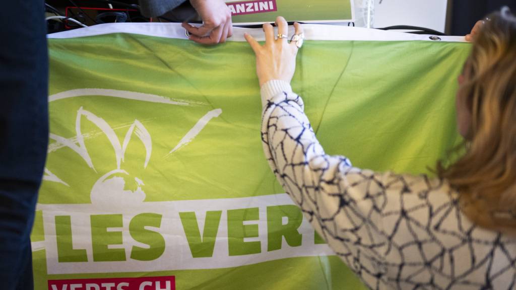 Delegierte hängen ein Transparent am Rednerpult an der Delegiertenversammlung der Grünen Schweiz in Chur auf.