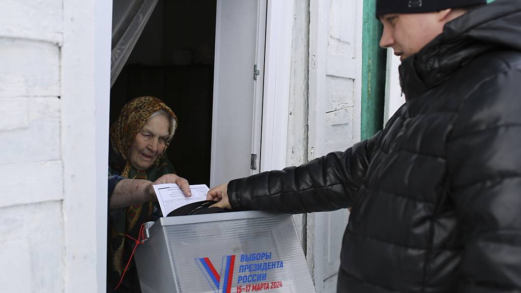 Eine ältere Frau gibt mit Hilfe eines mobilen Wahlkomitees ihre Stimme ab. Die Wähler in Russland gehen zu den Urnen, um an den Präsidentschaftswahlen teilzunehmen, bei denen es so gut wie sicher ist, dass die Präsidentschaft von Putin verlängert wird. Foto: ---/AP/dpa