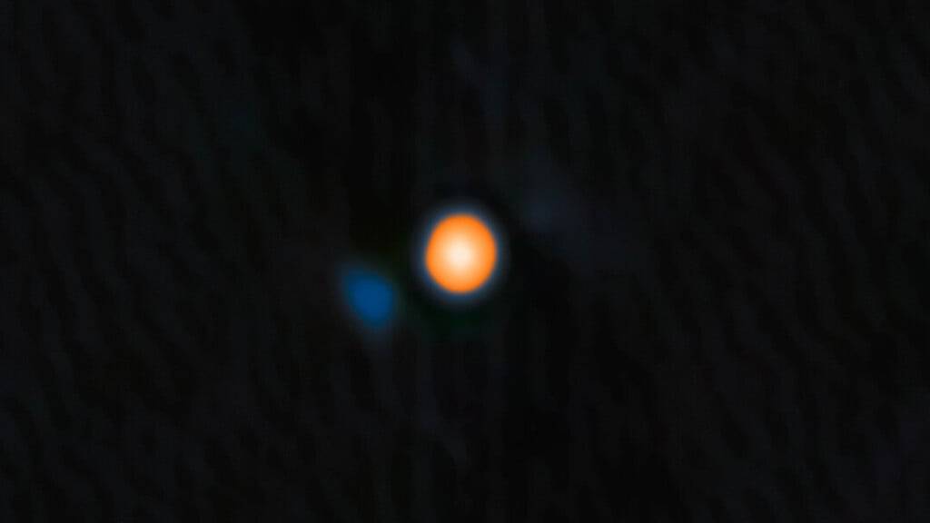 Mithilfe des Gemini-Nord-Teleskops haben Astronominnen und Astronomen einen Stern entdeckt, der in einer sehr engen Umlaufbahn um den Stern  Beteigeuze kreist. Auf dem Bild erscheint der sogenannte Begleitstern in blau.