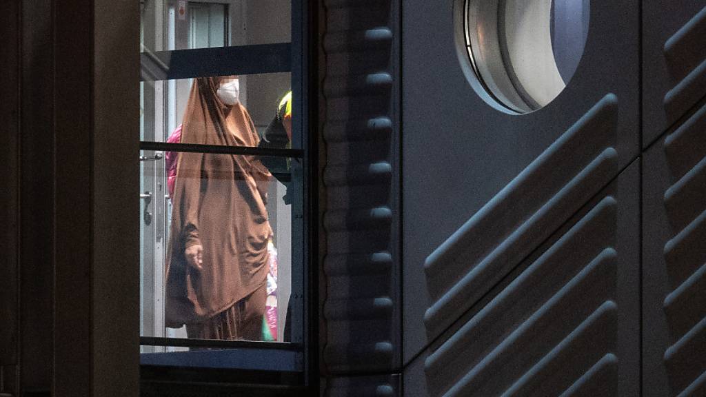 Eine verschleierte Frau mit einer Maske betritt aus der Gangway einer Chartermaschine heraus einen abgeschirmten Bereich der Bundespolizei am Flughafen Frankfurt. Foto: Boris Roessler/dpa