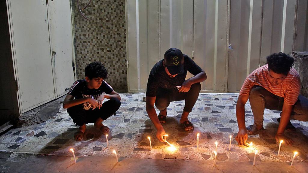 Menschen zünden Kerzen am Ort eines Bombenanschlags auf einem Markt in Bagdad an. Nach Angaben des irakischen Ministerpräsidenten ist die verantwortliche Terrorzelle gefasst worden. Foto: Khalid Mohammed/AP/dpa