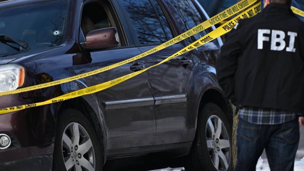 Ein Einschussloch in der Windschutzscheibe eines Autos ist zu sehen, als Polizeibeamte einen Tatort nach einem Einsatz untersuchen, an dem Bundespolizisten beteiligt waren. Bei einem umstrittenen Einsatz der US-Einwanderungsbehörde ICE im Bundesstaat Minnesota ist eine Frau durch einen Beamten erschossen worden. Foto: Tom Baker/AP/dpa