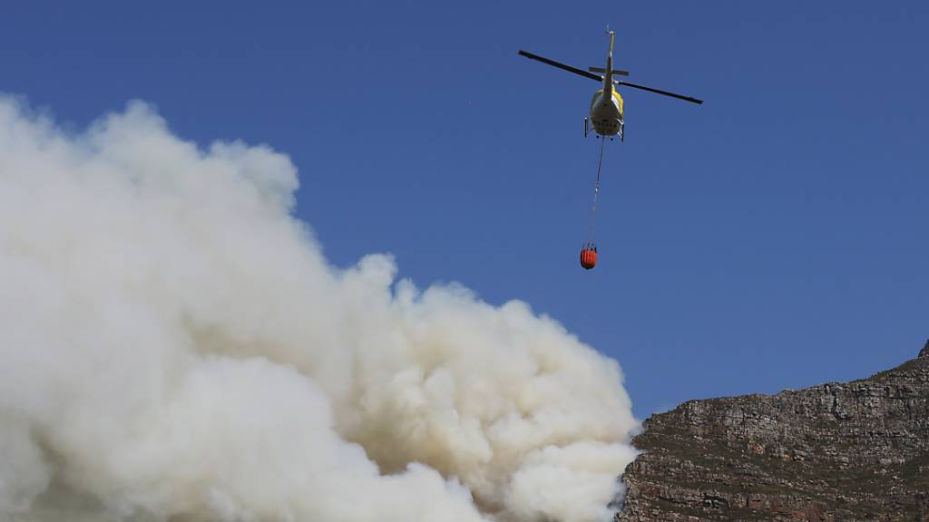 Ein Helikopter wirft Wasser über einem Brand auf dem Tafelberg ab. Foto: Nardus Engelbrecht/AP/dpa