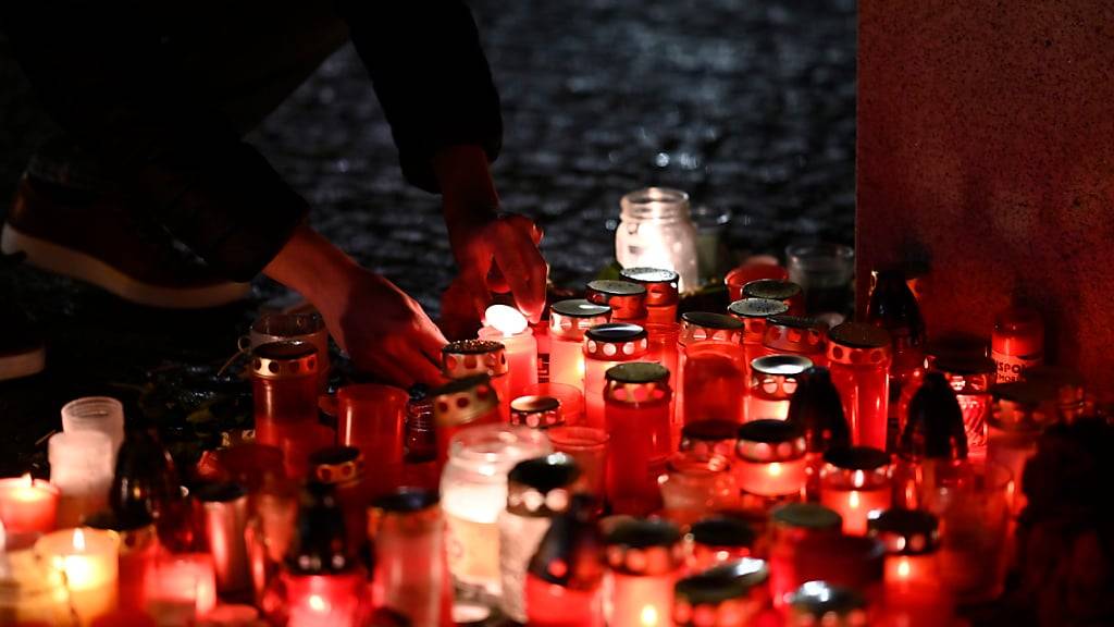 Eine Person entzündet eine Kerze vor dem Gebäude der Philosophischen Fakultät der Karls-Universität in Prag. Foto: Denes Erdos/AP/dpa