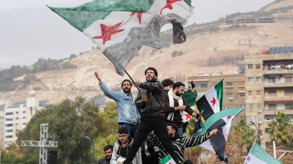 dpatopbilder - Syrer feiern auf dem Umayyad-Platz im Zentrum von Damaskus, während eine große Militärparade der syrischen Armee vorbeizieht, die den Jahrestag des Sturzes des Assad-Regimes feiert. Foto: Moawia Atrash/dpa