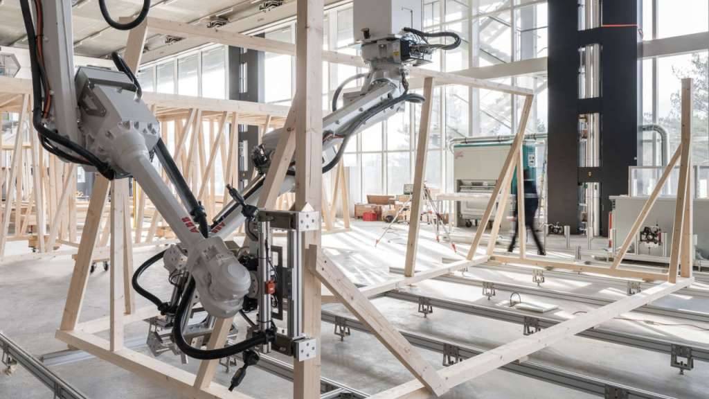 Zwei Roboter arbeiten beim Zusammenbau des Holzmoduls zusammen. Ihr Bewegungspfad wird laufend anhand des Baufortschritts berechnet.