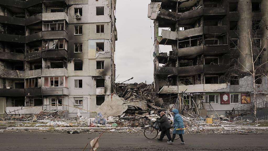 Frauen gehen an einem zerstörten Wohnhaus im ukrainischen Borodjanka vorbei. Foto: Vadim Ghirda/AP/dpa