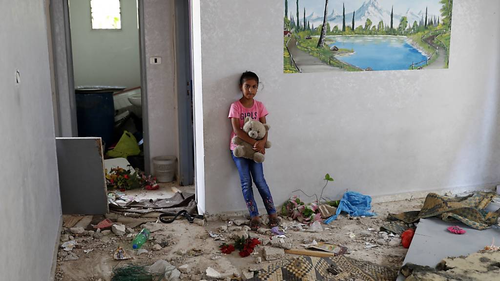 Die 10-jährige Rahaf Abu Fares, die vier Familienmitglieder verlor, als ihr Haus während des elftägigen Gefechts zwischen Israel und der Hamas im Mai von israelischer Artillerie bombardiert wurde, trägt einen Teddybär inmitten der Trümmer ihres Hauses im Beduinendorf Umm Al-Nasr. Foto: Adel Hana/AP/dpa