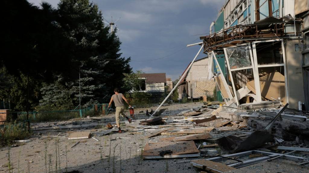 ARCHIV - Ein Anwohner läuft eine beschädigte Straße entlang, dem Schauplatz schwerer Kämpfe mit russischen Truppen in der Region Donezk. Foto: Yevhen Titov/AP/dpa (Archivbild)