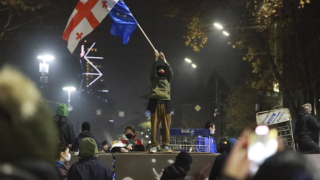 dpatopbilder - Ein Demonstrant steht mit georgischen National- und EU-Flaggen während einer Kundgebung vor dem Parlamentsgebäude in Tiflis. Foto: Zurab Tsertsvadze/AP/dpa