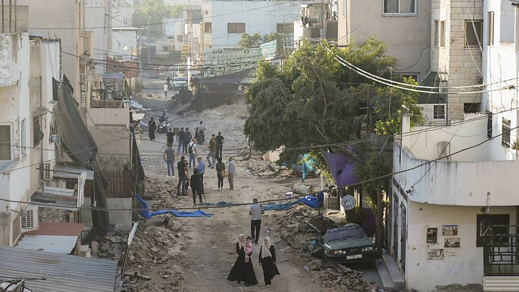 Palästinenser gehen auf einer beschädigten Straße in Dschenin nach dem Abzug israelischer Truppen. Foto: Majdi Mohammed/AP/dpa