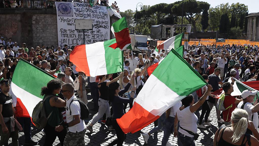 Teilnehmer einer Demonstration gegen die staatliche Corona-Politik schwenken italienische Nationalflaggen. Foto: Gregorio Borgia/AP/dpa