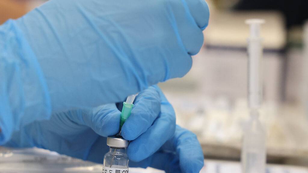 Eine medizinische Mitarbeiterin zieht den Impfstoff von Biontech in eine Spritze. Foto: Bodo Schackow/dpa-Zentralbild/dpa