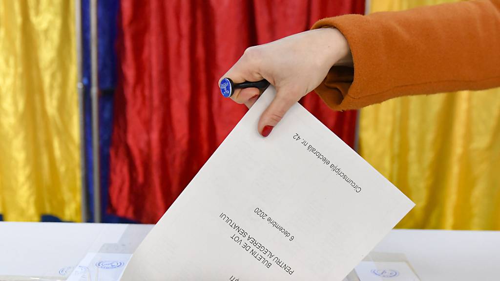 Eine Frau gibt ihren Stimmzettel ab. Foto: Andreea Alexandru/AP/dpa