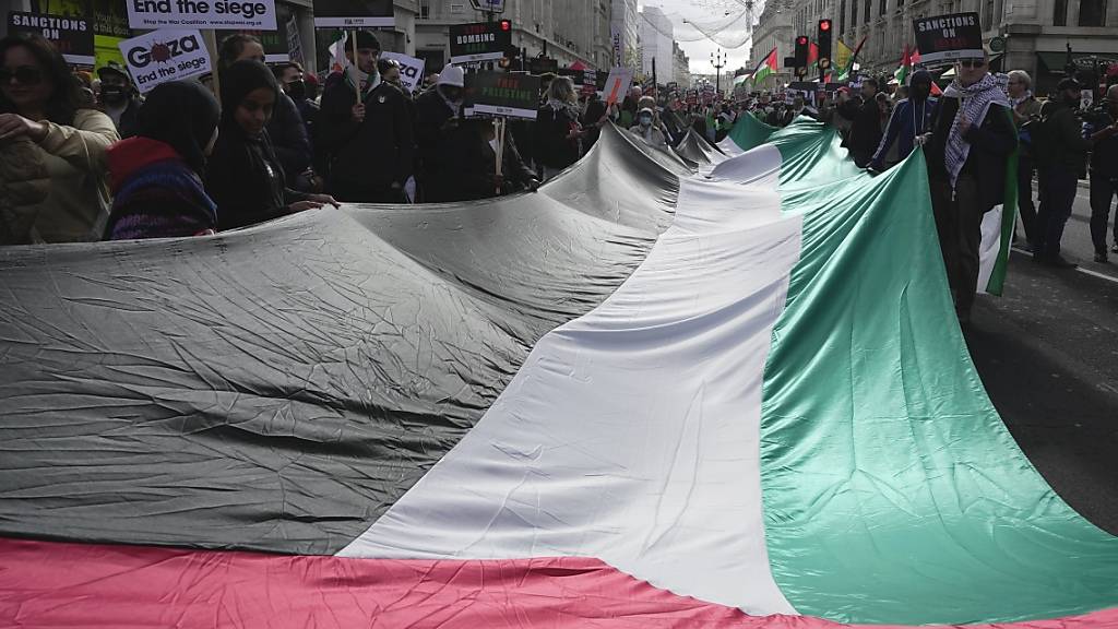 Zahlreiche Menschen halten eine riesige palästinensische Fahne während einer pro-palästinensischen Demonstration in London. Foto: Kin Cheung/AP/dpa