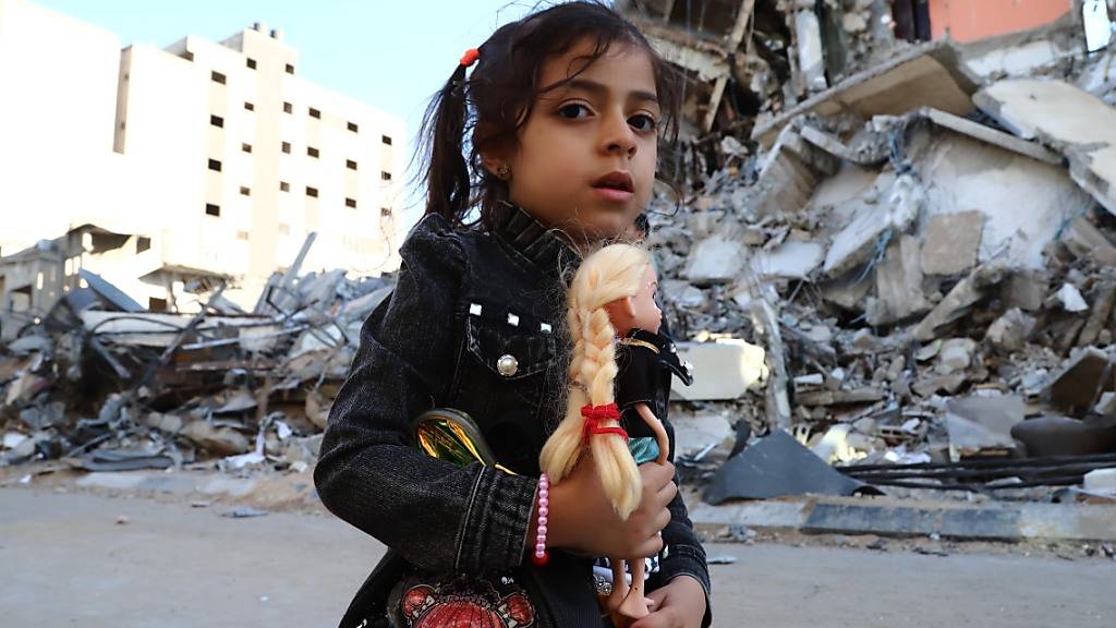 dpatopbilder - Ein Mädchen geht vorbei an von Luftangriffen zerstörten Häusern. Seit dem 10. Mai beschießen militante Palästinenser Israel mit Raketen. Israels Armee reagiert darauf mit Angriffen auf Ziele im Gazastreifen, vor allem durch die Luftwaffe. Auf beiden Seiten gab es Tote. Foto: Naaman Omar/APA Images via ZUMA Wire/dpa