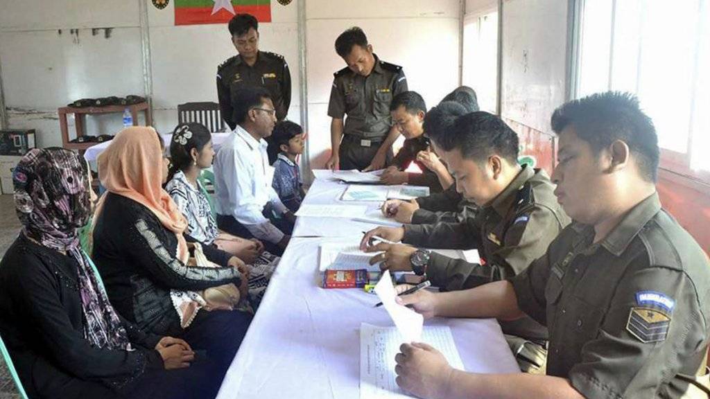 Myanmarische Militärs stellen der Rohingya-Familie Papiere aus.