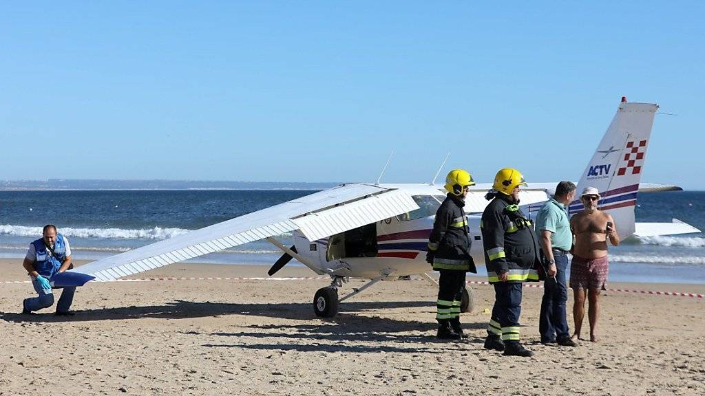 Rettungskräfte prüfen das Kleinflugzeug. Die Maschine hatte bei einer Notlandung an einem belebten Strand in Portugal zwei Badegäste in den Tod gerissen.