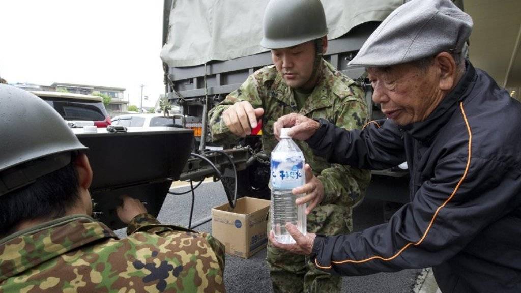 Sicherheitskräfte verteilen Wasser an Erdbebenopfer in der Stadt Mashiki in der Provinz Kumamoto. In den Notaufnahmelagern herrscht nach der Erdbebenserie in Japan mit mindestens 42 Toten weiter Mangel an Lebensmitteln.