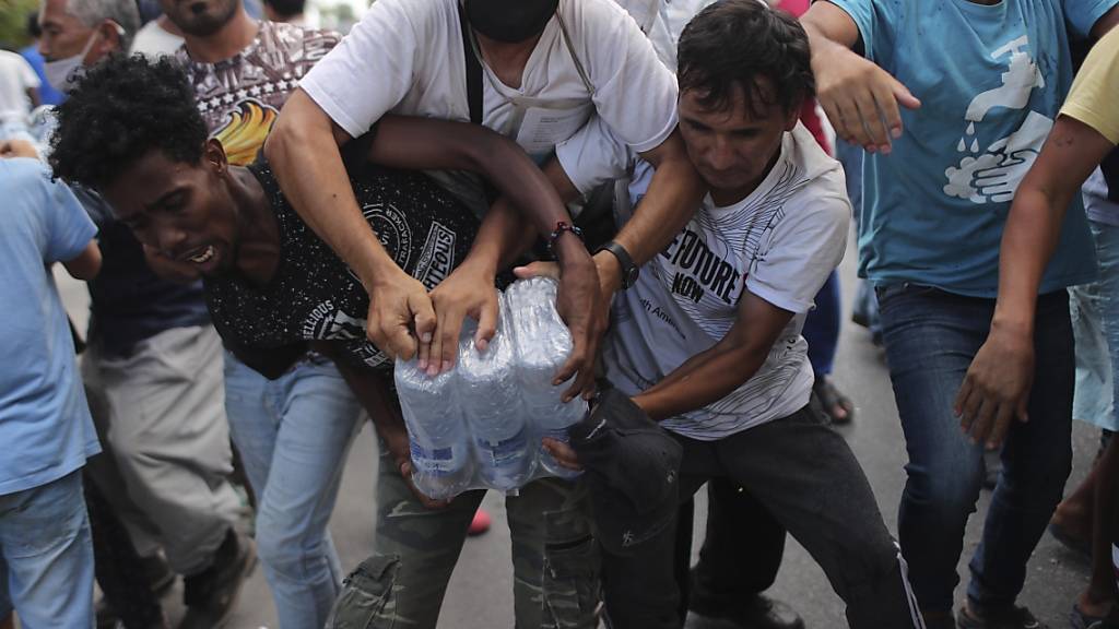 dpatopbilder - Migranten ringen um Wasserflaschen. Foto: Petros Giannakouris/AP/dpa