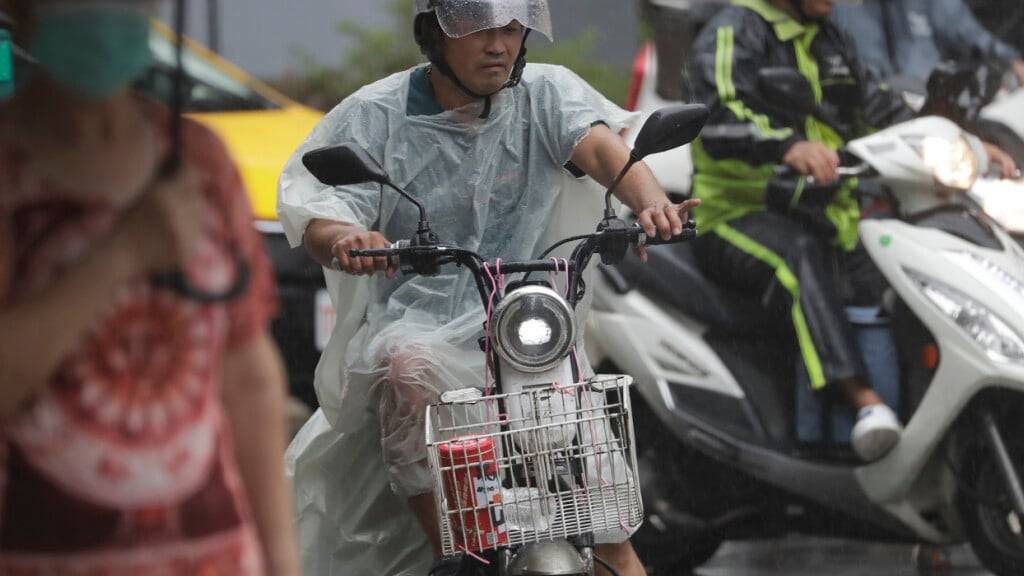 Passanten schützen sich vor dem Regen, während der Taifun Danas über Taiwan hinwegzieht. Foto: Chiang Ying-ying/AP/dpa