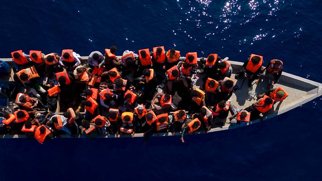 ARCHIV - Menschen sitzen in einem Holzboot im Mittelmeer. Symbolbild Foto: Joan Mateu Parra/AP/dpa