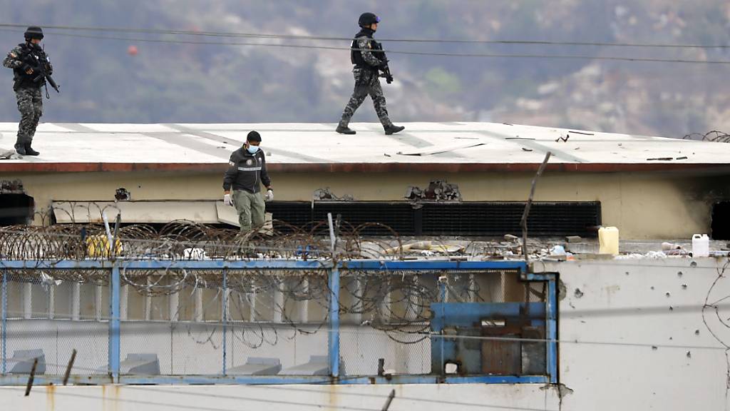 dpatopbilder - Polizisten laufen über das Dach eines Gefängnisses, nachdem dort Unruhen ausbrachen. Bei erneuten gewalttätigen Auseinandersetzungen in einem Gefängnis in Ecuador sind Medien zufolge mindestens 58 Häftlinge ums Leben gekommen. (zu dpa: «Mindestens 68 Tote bei erneuten Kämpfen in Gefängnis in Ecuador») Foto: Jose Sanchez/AP/dpa