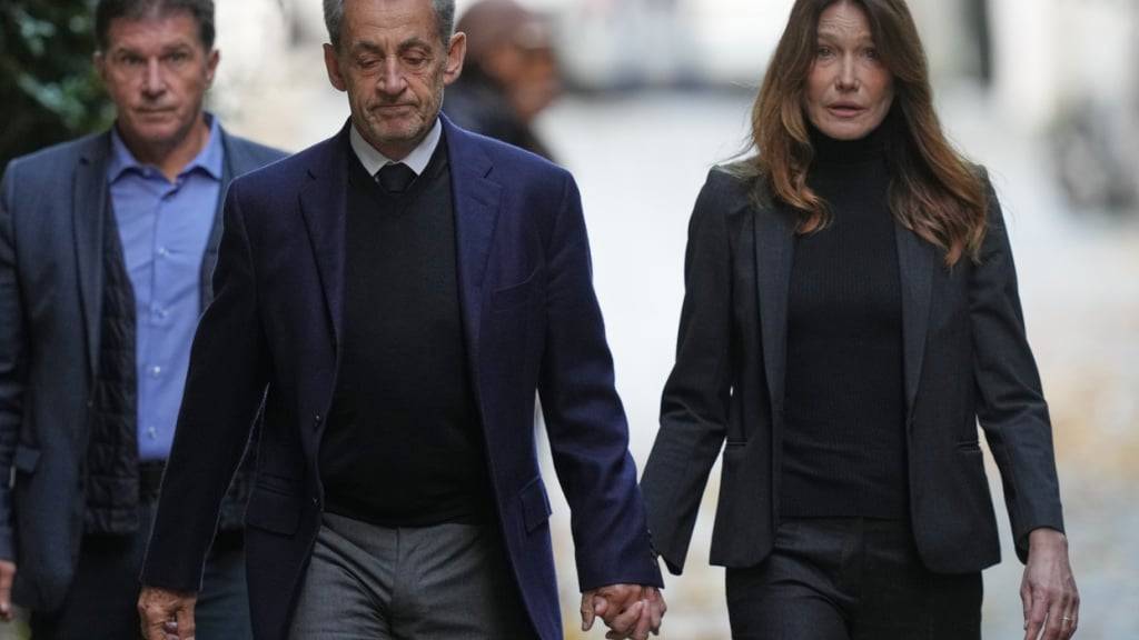 ARCHIV - Der ehemalige französische Präsident Nicolas Sarkozy und seine Frau Carla Bruni-Sarkozy verlassen ihr Haus in Paris, während Sarkozy ins Gefängnis geht, um seine Strafe für eine kriminelle Verschwörung zur Finanzierung seines Wahlkampfes 2007 mit Geldern aus Libyen abzusitzen. Foto: Thibault Camus/AP/dpa
