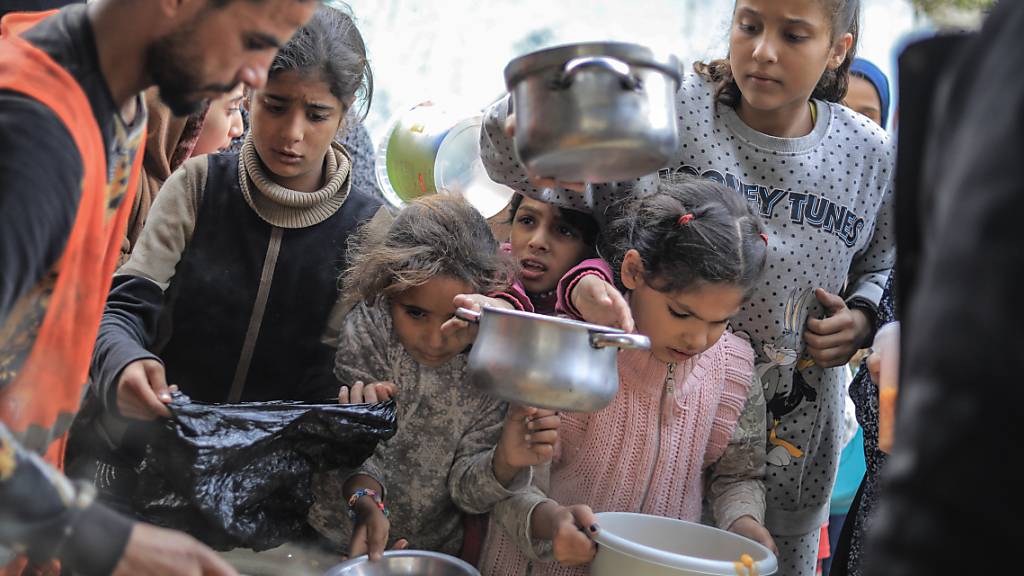 dpatopbilder - Die Not im Gazastreifen wird immer schlimmer. Menschen stehen in Rafah im Süden des abgeriegelten Küstengebiets mit Töpfen, Schalen und Tüten bei einer Essensausgabe an. Foto: Mohammed Talatene/dpa