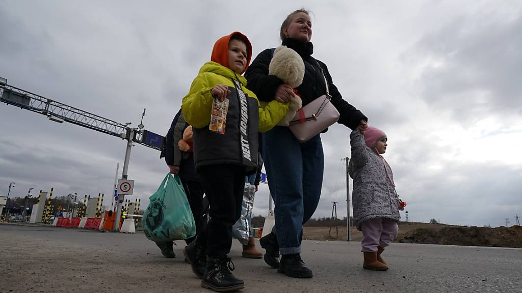 Eine Frau geht mit ihren Kindern eine Straße entlang, nachdem sie die ukrainisch-polnische Grenze passiert haben. Foto: Bryan Smith/ZUMA Press Wire/dpa