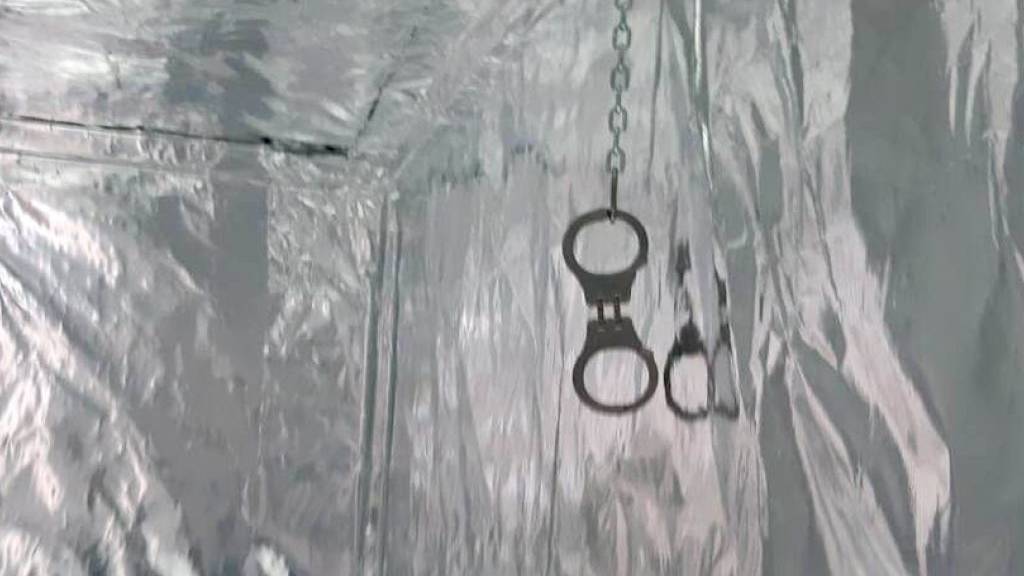 Handschellen hängen von einer Decke. Die niederländische Polizei hat ein Gefängnis der Unterwelt mit einer Folterkammer entdeckt. Insgesamt sieben Container seien von einer kriminellen Bande umgebaut worden, teilte die Staatsanwaltschaft mit.