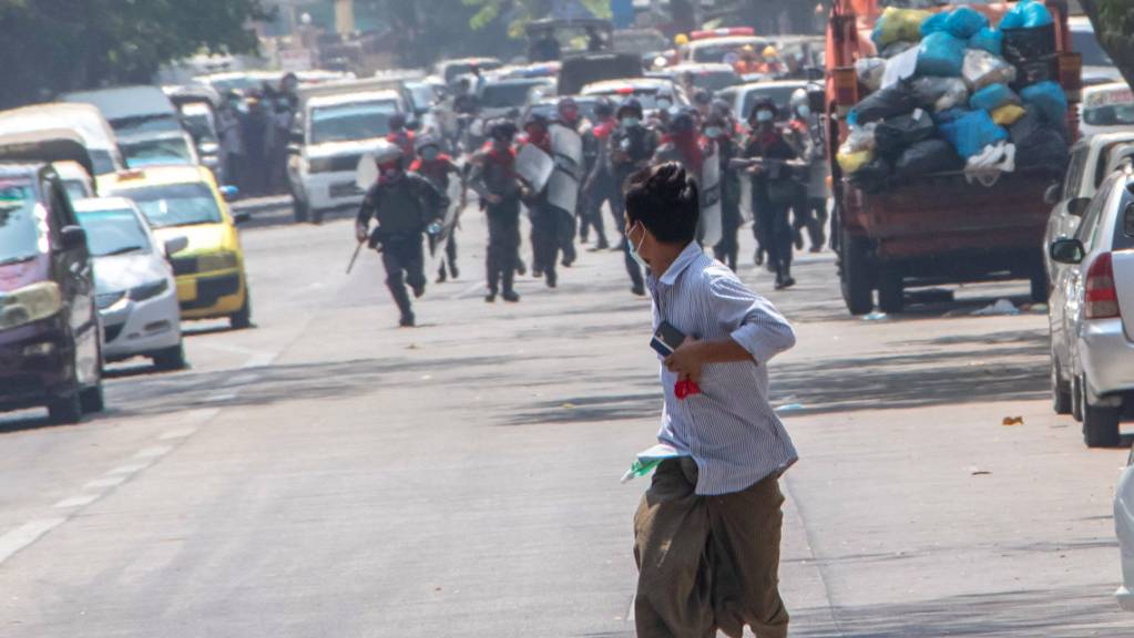 ARCHIV - Bereitschaftspolizisten rennen einem Demonstranten in Rangun hinterher. (Archivbild) Foto: Santosh Krl/SOPA Images via ZUMA Wire/dpa