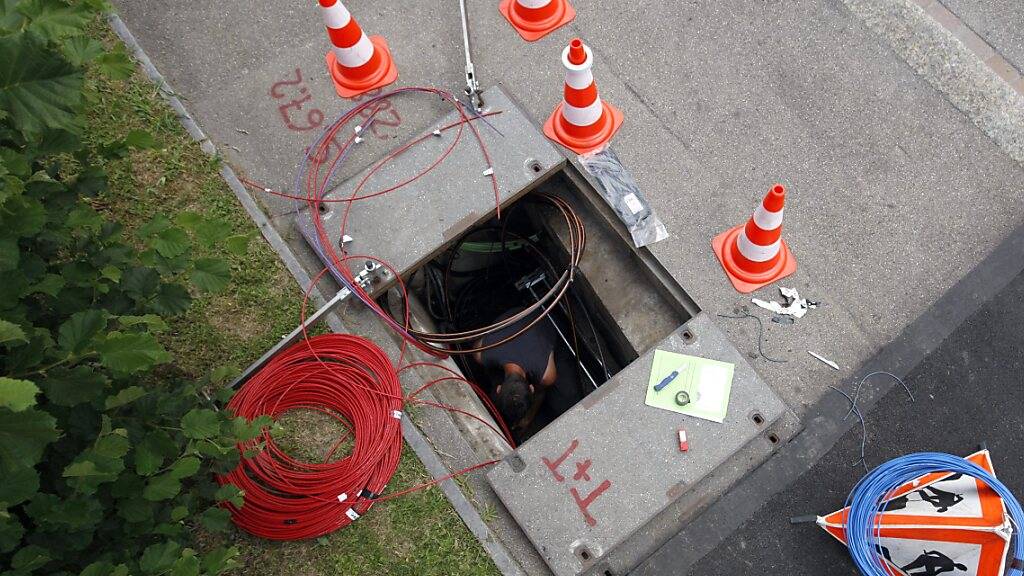 Ein Techniker installiert 2009 in Zürich für die Swisscom Glasfaserkabel. (Archivbild)