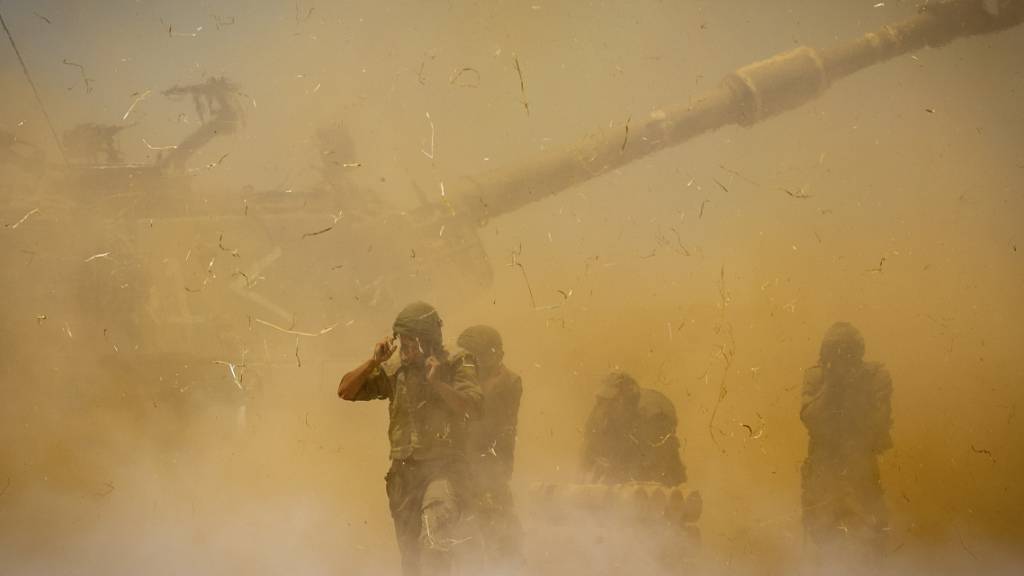 dpatopbilder - Israelische Soldaten stehen in aufgewirbeltem Staub, nachdem ein Artilleriegeschütz auf Ziele im Gazastreifen gefeuert hat. Foto: Yonatan Sindel/AP/dpa