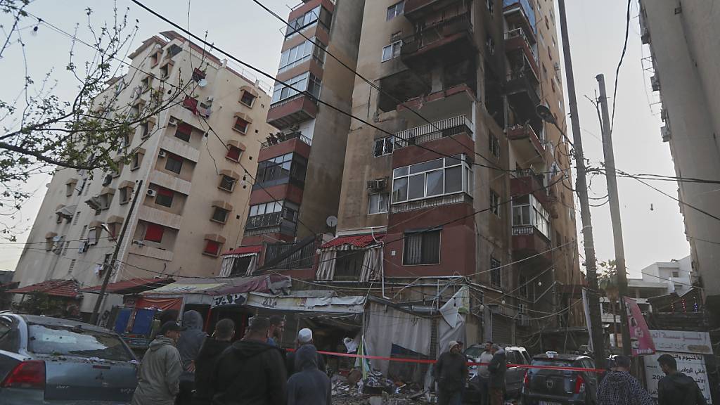 Anwohner versammeln sich in der Nähe einer zerstörten Wohnung, die von einem vermeintlich israelischen Luftangriff getroffen wurde, in der südlichen Hafenstadt Sidon. Foto: Mohammad Zaatari/AP/dpa