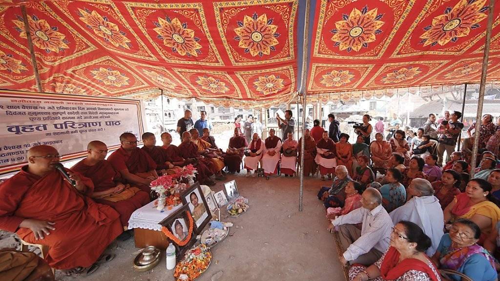 Buddhistische Mönche beten mit Angehörigen für die Opfer des Erdbebens in Nepal vor einem Jahr.