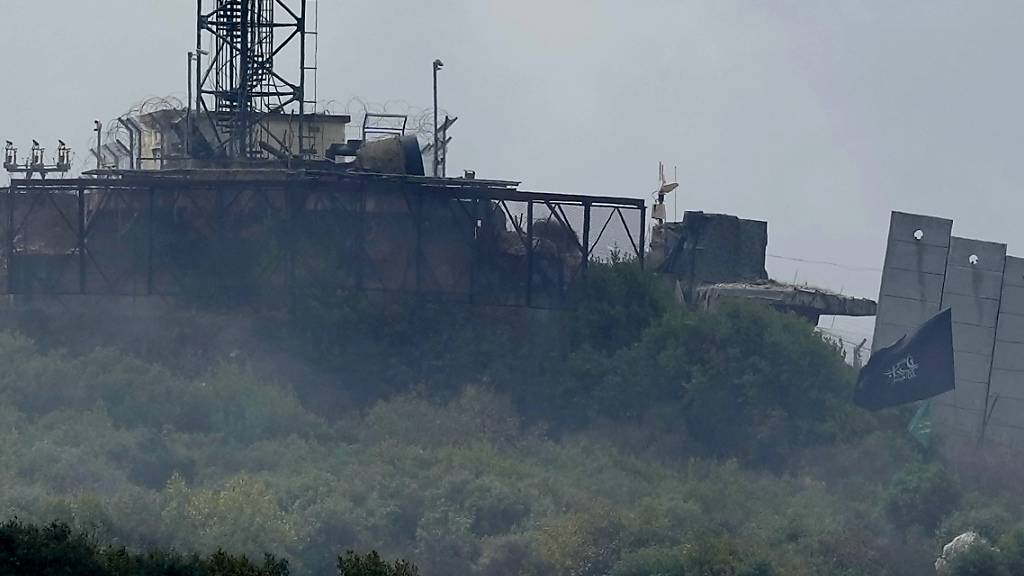 Eine schwarze Fahne (r) mit der arabischen Aufschrift «Oh Hussein» wurde von Hisbollah-Kämpfern am Zaun einer israelischen Armeestellung angebracht. Foto: Hussein Malla/AP/dpa