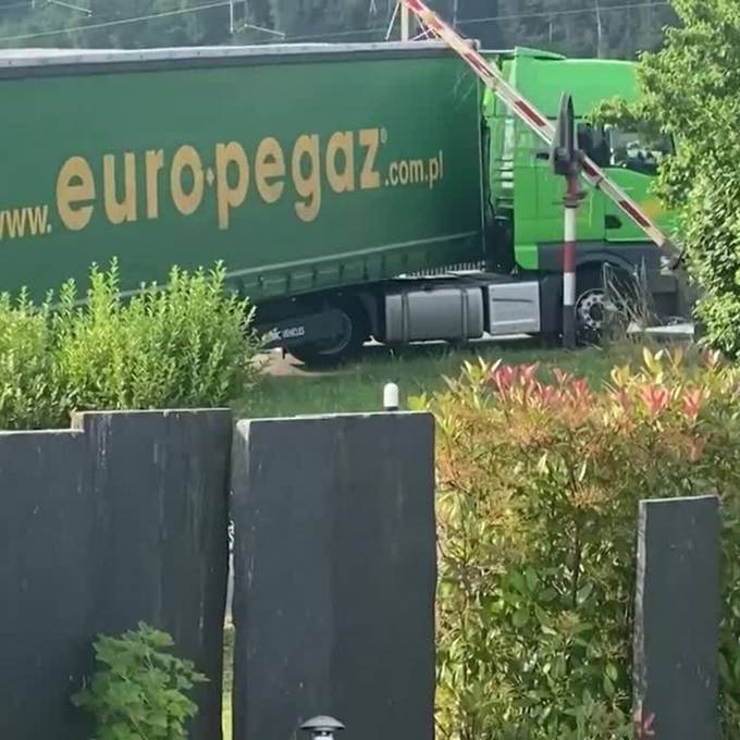 Lastwagenchauffeur verfängt sich an Barriere auf Bahnübergang