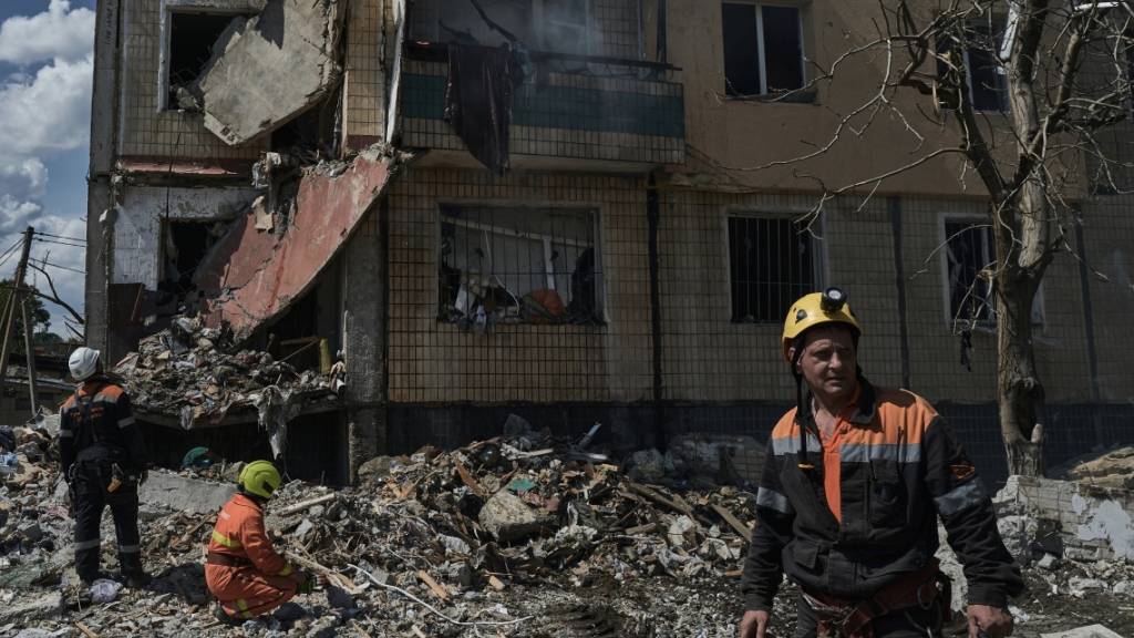 Ukrainische Rettungskräfte sind nach dem Einschlag einer Rakete in einem Wohnhaus in Krywyj Rih im Einsatz. Foto: Libkos/AP/dpa
