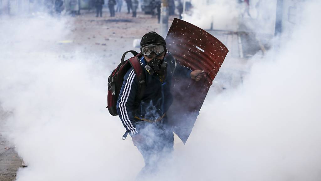 Ein Anti-Regierungs-Protestler läuft durch Wolken von Tränengas während Zusammenstößen mit der Polizei. Kolumbianer sind seit Wochen im ganzen Land auf die Straße gegangen.In der Stadt Cali waren am Freitag und in der Nacht zum Samstag Medien zufolge mindestens sechs Menschen im Zusammenhang mit den Demonstrationen ums Leben gekommen. Foto: Ivan Valencia/AP/dpa