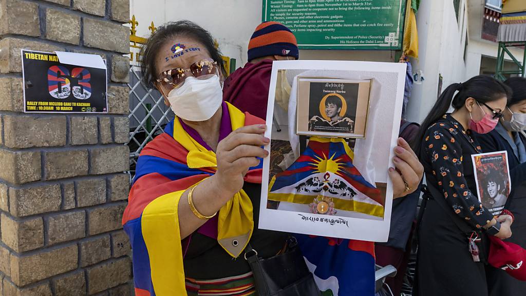 Eine Frau zeigt während einer Versammlung zum Jahrestag des tibetischen Aufstands von 1959 ein Porträt von Tsewang Norbu, einem jungen Sänger, der sich nach exiltibetischen Angaben selbst angezündet hat.
