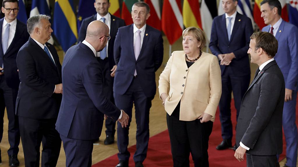 Angela Merkel (M) spricht mit Charles Michel (Mitte links), Präsident des Europäischen Rates, und Emmanuel Macron (rechts), Präsident von Frankreich. Beim Gipfel der EU-Staats- und Regierungschefs ist es zu keiner Einigung gekommen, wie langfristig gegen hohe Energiepreise vorgegangen werden soll. Foto: Olivier Matthys/AP/dpa
