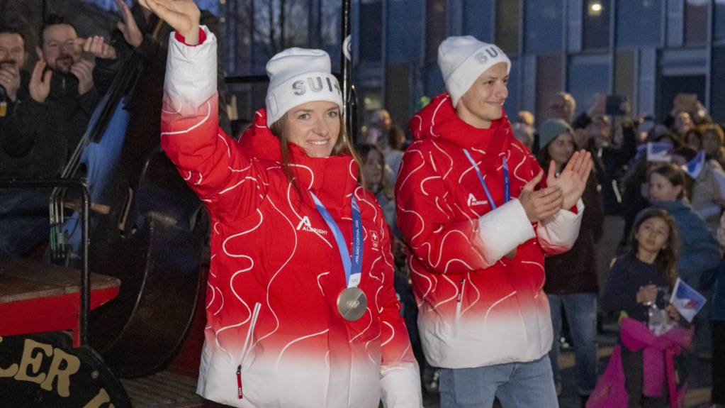 Nadine Fähndrich (links) und Gregor Deschwanden mit ihren Olympia-Medaillen beim Einzug in die Mehrzweckhalle von Horw, wo sie dem örtlichen Skiclub angehören.
