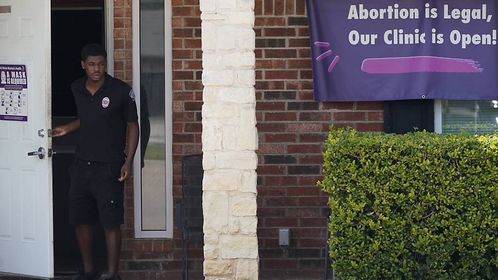 Ein Wachmann öffnet die Tür der Whole Women's Health Clinic, an der ein Banner mit der Aufschrift «Abortion is Legal, Our Clinic is Open!» («Abtreibung ist legal, unsere Klinik ist geöffnet!») hängt. Foto: Lm Otero/AP/dpa