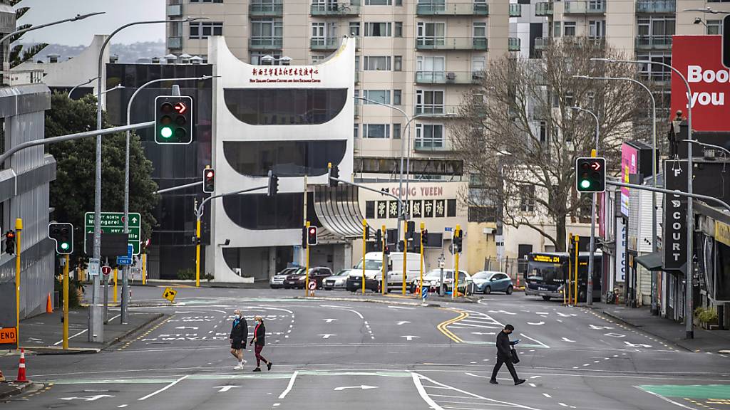 Menschen überqueren im zentralen Geschäftsviertel fast leere Straßen. Aufgrund von sinkenden Corona-Zahlen wird nach einem Monat des strengen Lockdowns in der neuseeländischen Millionenmetropole Auckland gelockert. Das teilte die Regierung am Montag mit. Foto: Michael Craig/New Zealand Herald/dpa