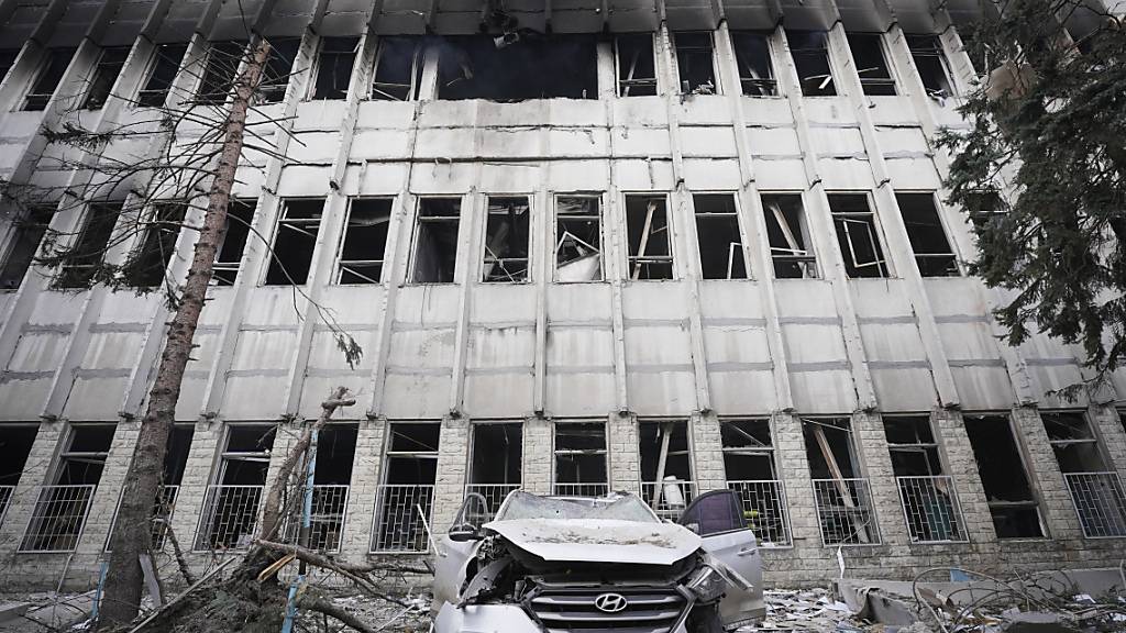 Ein zerstörtes Auto steht inmitten von Trümmern vor einem beschädigten Gebäude nach einem russischen Angriff. Foto: Andrii Marienko/AP/dpa