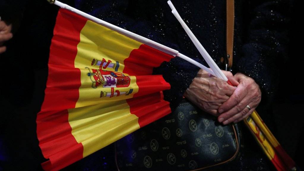 Eine Frau hält Fähnchen mit der spanischen Flagge in ihren Händen. Spaniens König Felipe hat Neuwahlen für den 26. Juni ausgerufen. (Archiv)