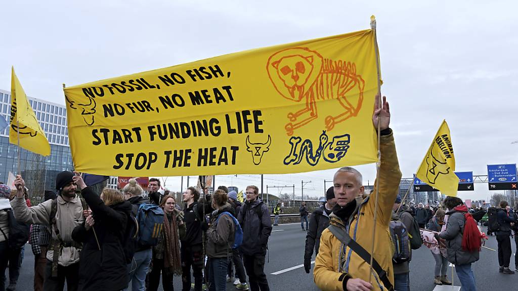 Klimaaktivisten blockieren die Hauptstraße um Amsterdam in der Nähe des ehemaligen Hauptsitzes einer ING-Bank, um gegen deren Finanzierung fossiler Brennstoffe zu protestieren. Foto: Patrick Post/AP/dpa